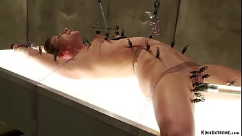 Strapped brunette MILF slave Ariel X in laid on illuminating table and clamped then machine fucked till tormented in black straitjacket at Psycho Ward